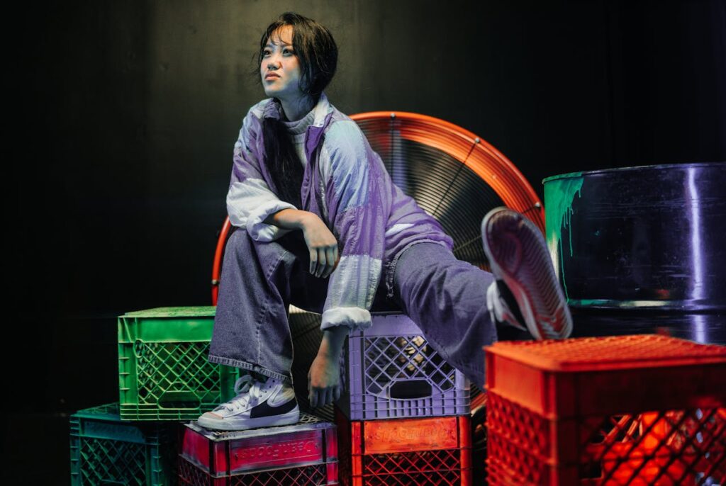 Fashionable woman posing on vibrant crates in a stylish indoor setting.