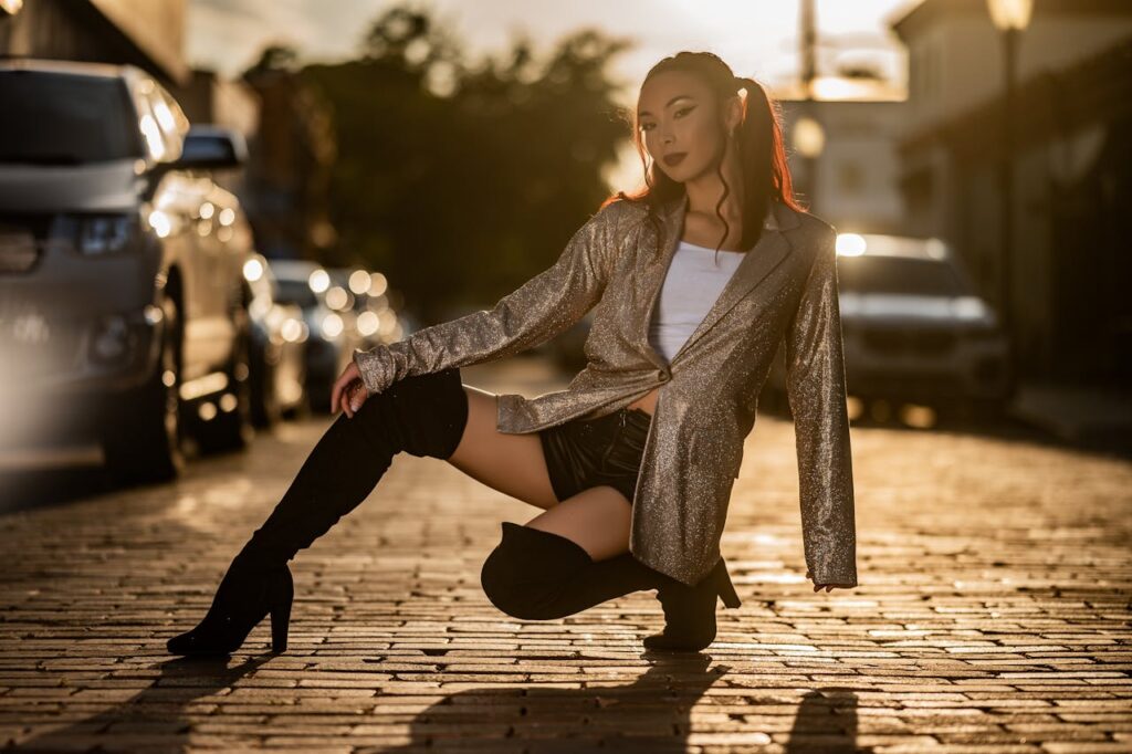 Fashionable woman in a stylish outfit poses on a city street during sunset.