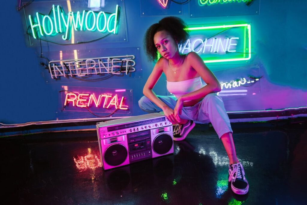 Fashionable woman posing with a boombox in a vibrant neon-lit setting, showcasing urban style.